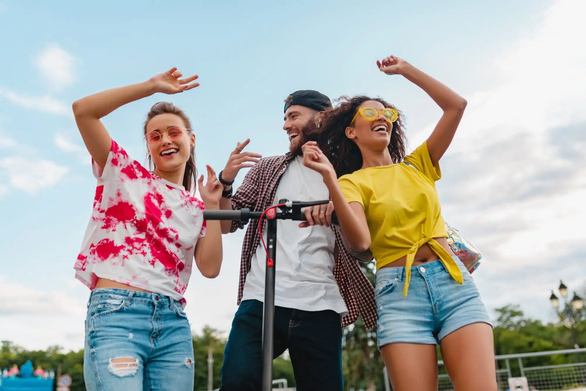 Your Guide to Austin Events Near The Johnny - Happy young company of smiling friends dancing walking in Street with an electric kick scooter, a man and a woman having fun together.